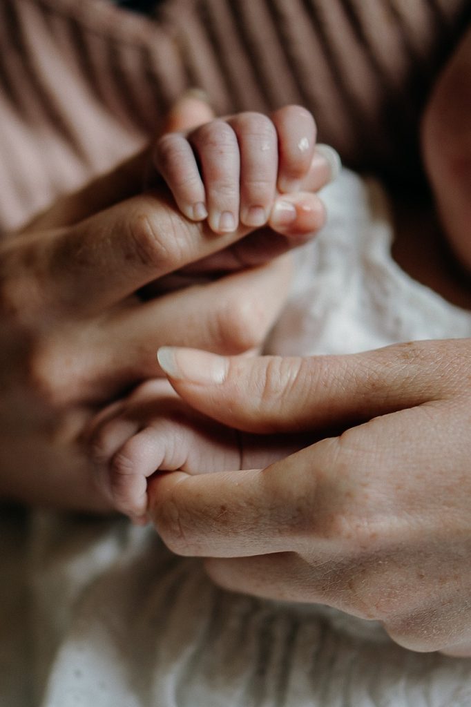 doigts adultes tenus par les mains d'un bébé